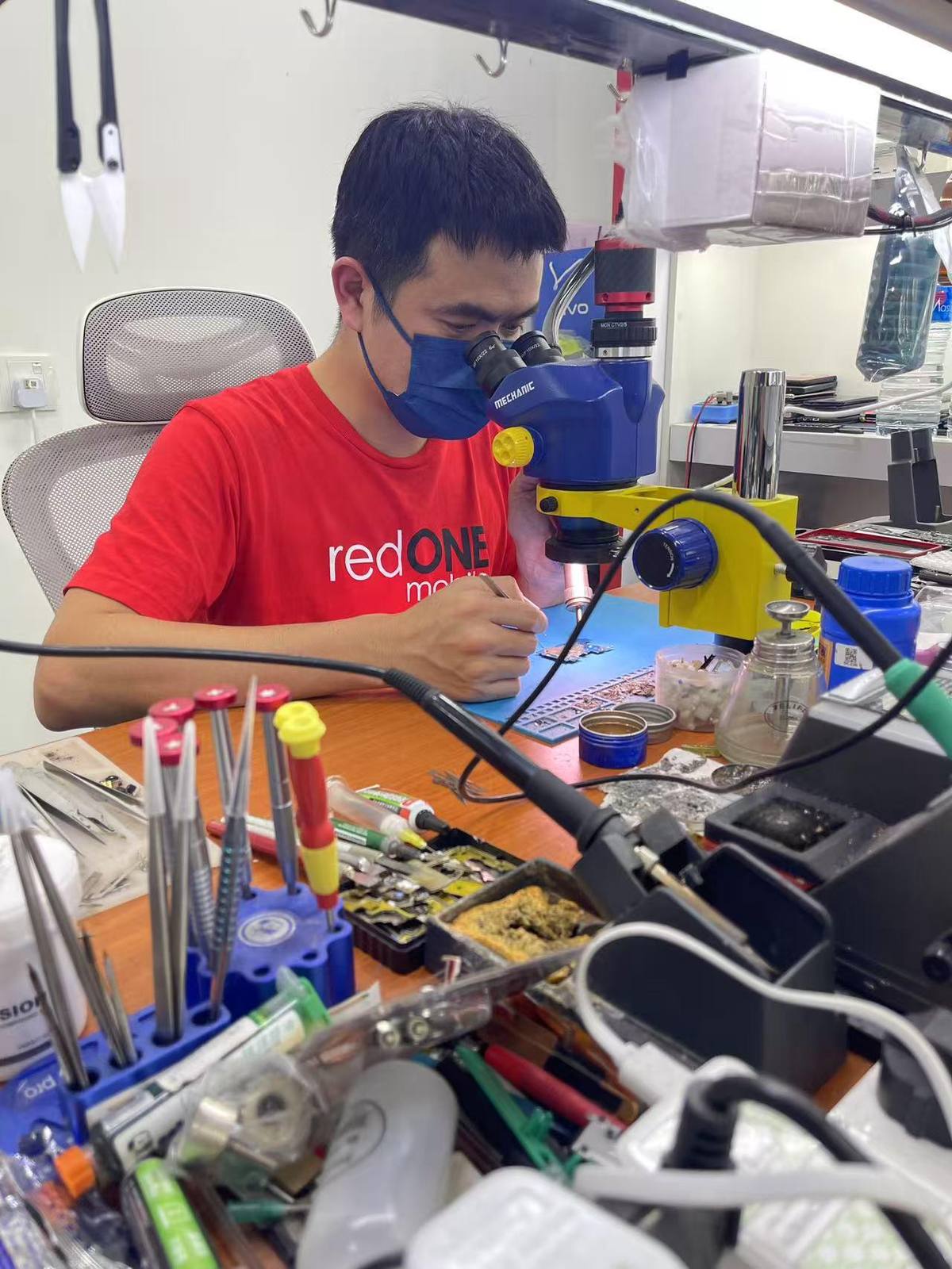 Lim Kok Tong repairing a motherboard under a microscope